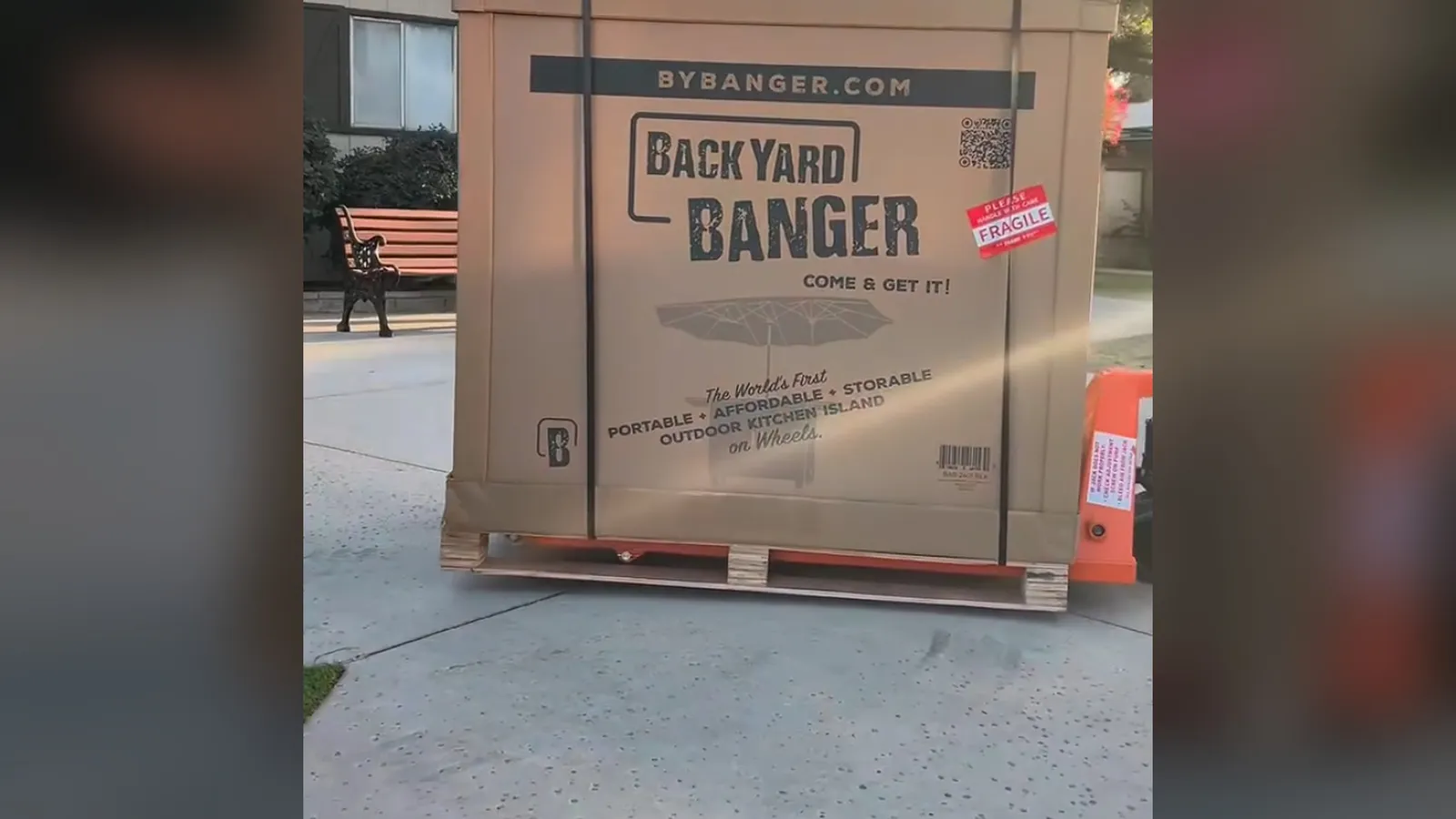 The Backyard Banger's shipping crate strapped to a pallet on a pallet jack, printed with the Backyard Banger logo.