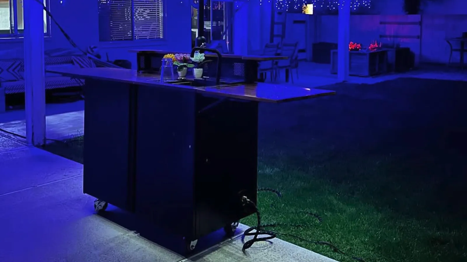 The Banger on a patio at night, lit blue, under a string-lit umbrella.